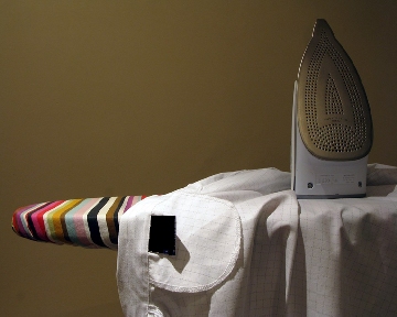 Iron standing on ironing board with shirt